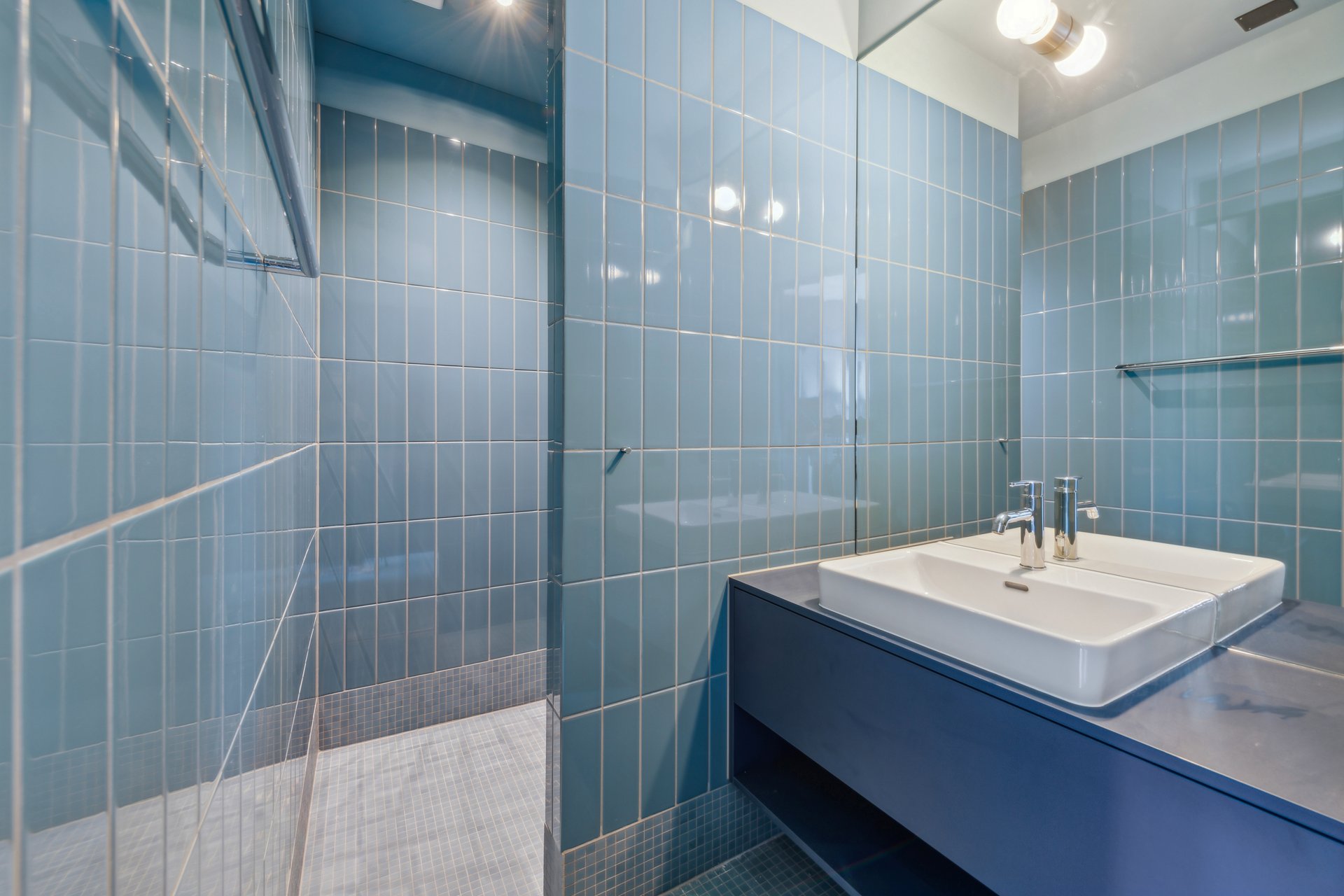 Badezimmer mit blauen Plättli und blauem Waschtischmöbel